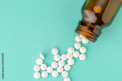 White round tablets scattered near glass bottle of pills