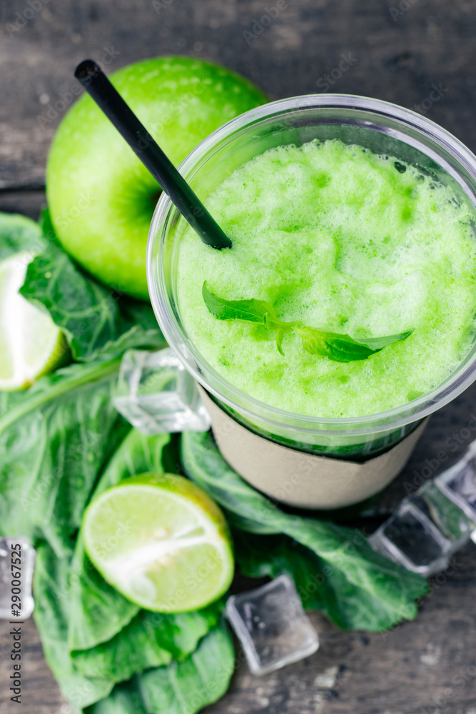 Green apple smoothie in glass and kale leaves on wooden table Green apple smoothie in glass and kale leaves on wooden table