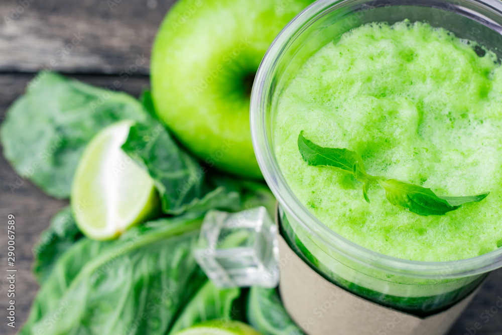 Green apple smoothie in glass and kale leaves on wooden table Green apple smoothie in glass and kale leaves on wooden table