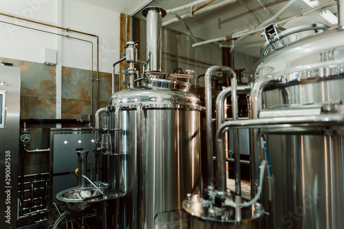 Microbrewery equipment. Close up tanks in brewery warehouse. Metal brewery vessels. Small business concept.