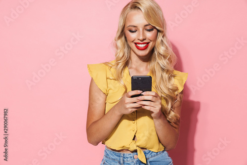 Image of young woman with long blond hair smiling and holding cellphone