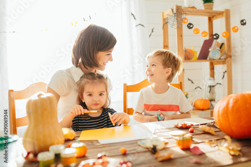 family mother and child daughter in hat witch are preparing for Halloween carve a pumpkin and decorate the house Happy Halloween concept