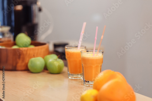 Two servings of fruit juice with a straw in glass cups stand on the bar near the fruit vases. Detox cleansing concept