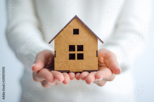 Woman holding wooden model house in hands on white background