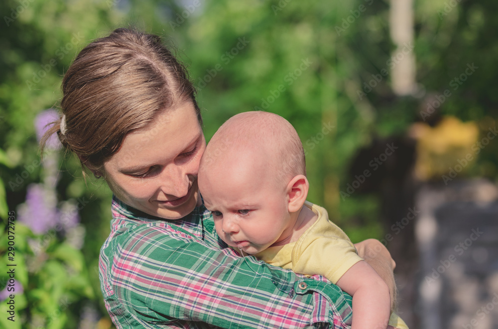 Close-up of a young mother holding a small baby in her arms Close-up of a young mother holding a small baby in her arms