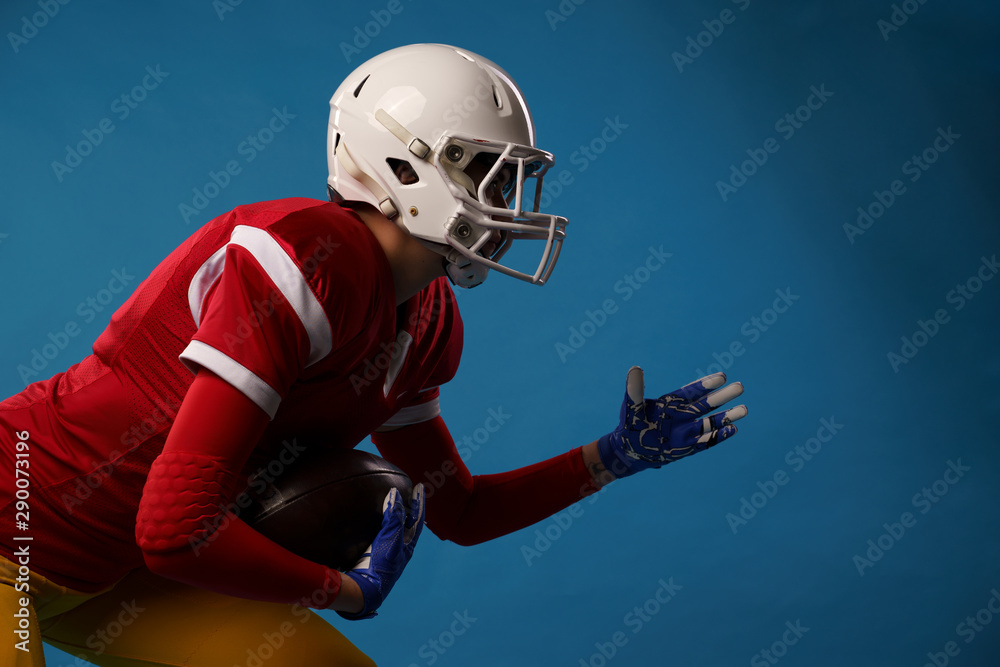 Side view of running sportswoman of american football player on blue background.