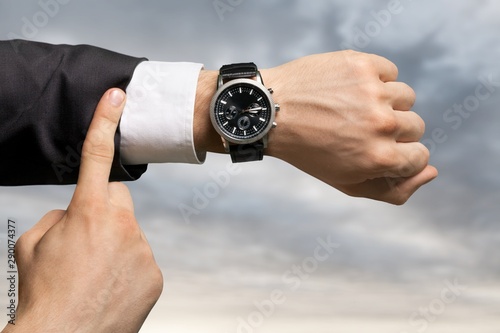 Businessman pointing at hand watch on grey