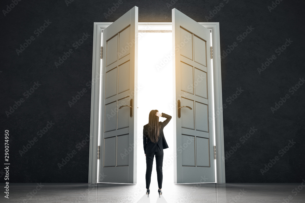 Fototapeta premium Decision making concept with businesswoman standing in front of white doors in abstract bright space.