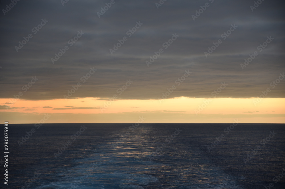 Sunset over the sea, view from the sailing cargo ship.