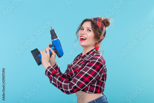 Sexy young pin-up woman with drill over blue background photo