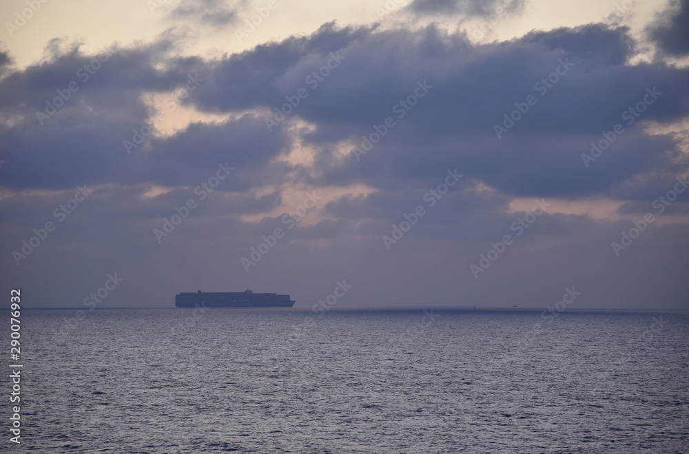 Sunrise near the Port Said, Egypt. Cargo ship on the horizon, waiting for Suez Canal transit.