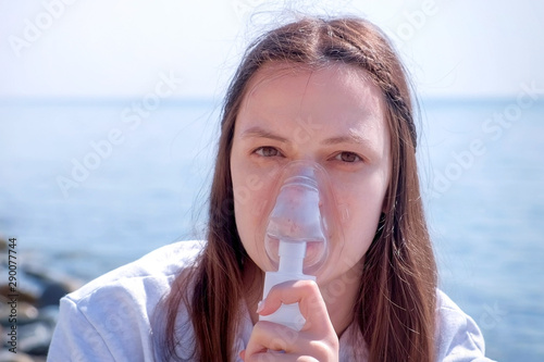 Foto Young sick woman use nebulizer on seaside