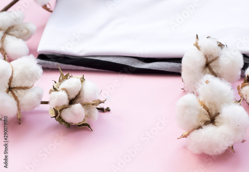 Delicate white cotton flowers textile clothes on a pink background. Organic cotton clothing idea