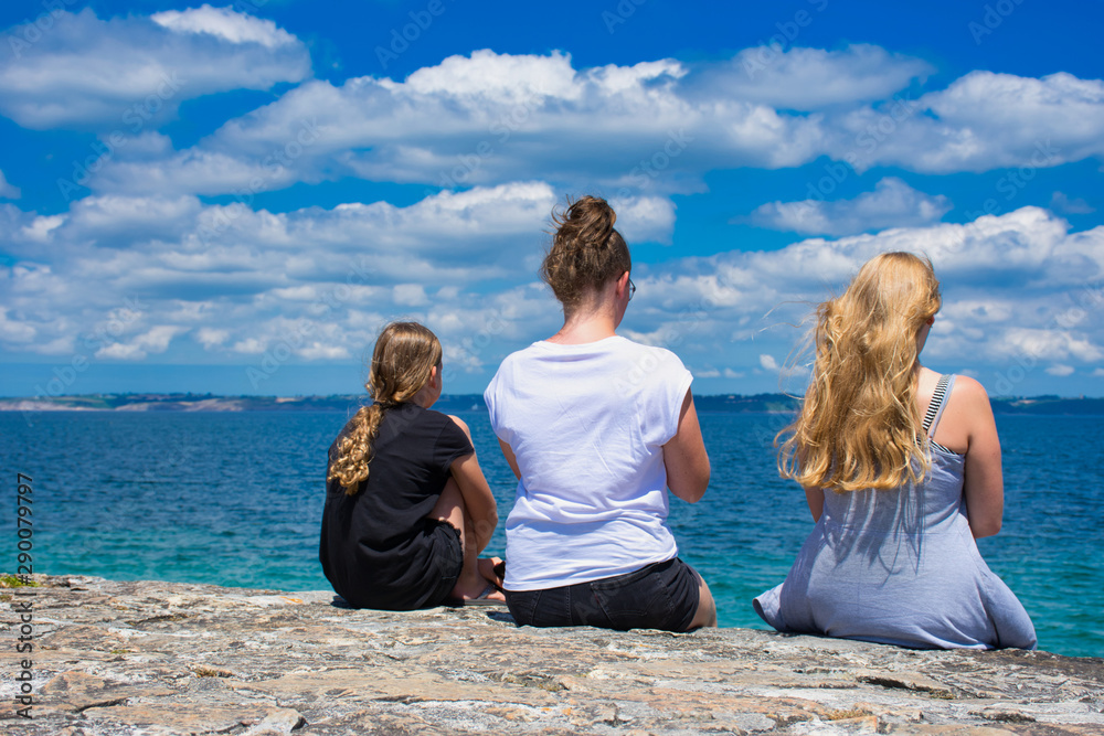Fototapeta premium three girls photographed from behind while they are looking to the ocean in Camaret-sur-Mer in France