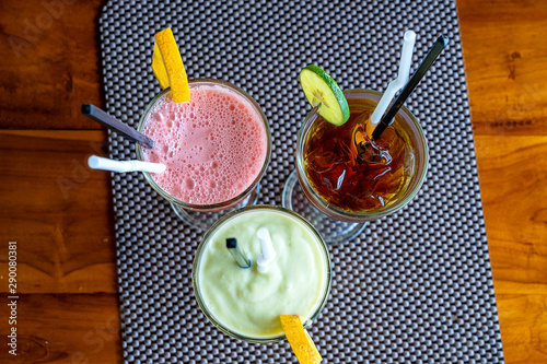 Avocado smoothie, watermelon shake and cold tea in a glass on a wooden table. Tropical drink concept . Top view, closeup