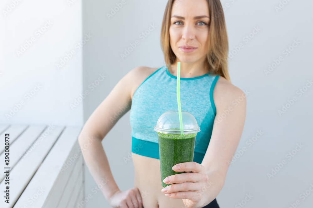 Healthy, sport, diet and people concept - Successful fitness urban woman recommending detox smoothie, close-up