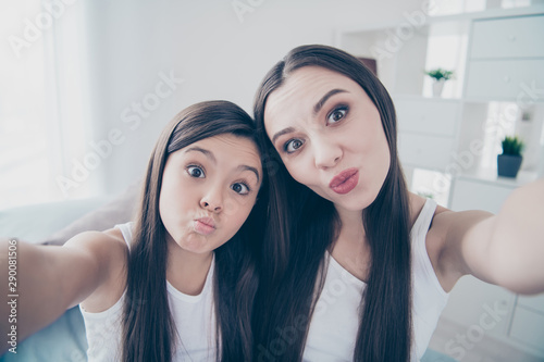 Self-portrait of two nice beautiful attractive sweet cheerful cheery comic foolish girlish long haired people having fun spending free spare time in light white interior room indoors