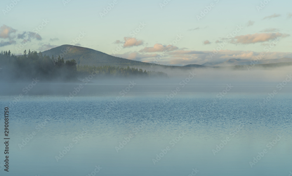Fog over a lake in scandinavia during a summers dawn. Jamtland, Sweden.