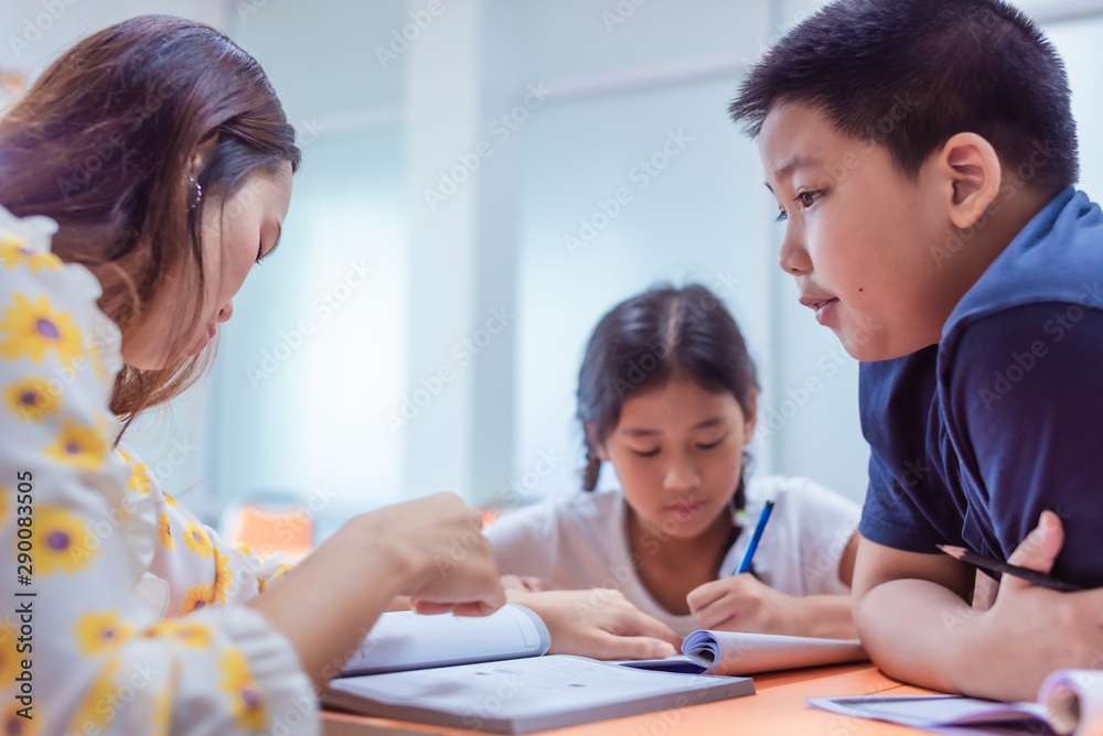 Asian elementary school girl and boy are studying and having fun in the classroom with female teachers.