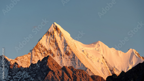 Beautiful golden Snow Mountain with blue sky background in sunset time, Peak Jambeyang, Daocheng Yading National Park, Sichuan, China.