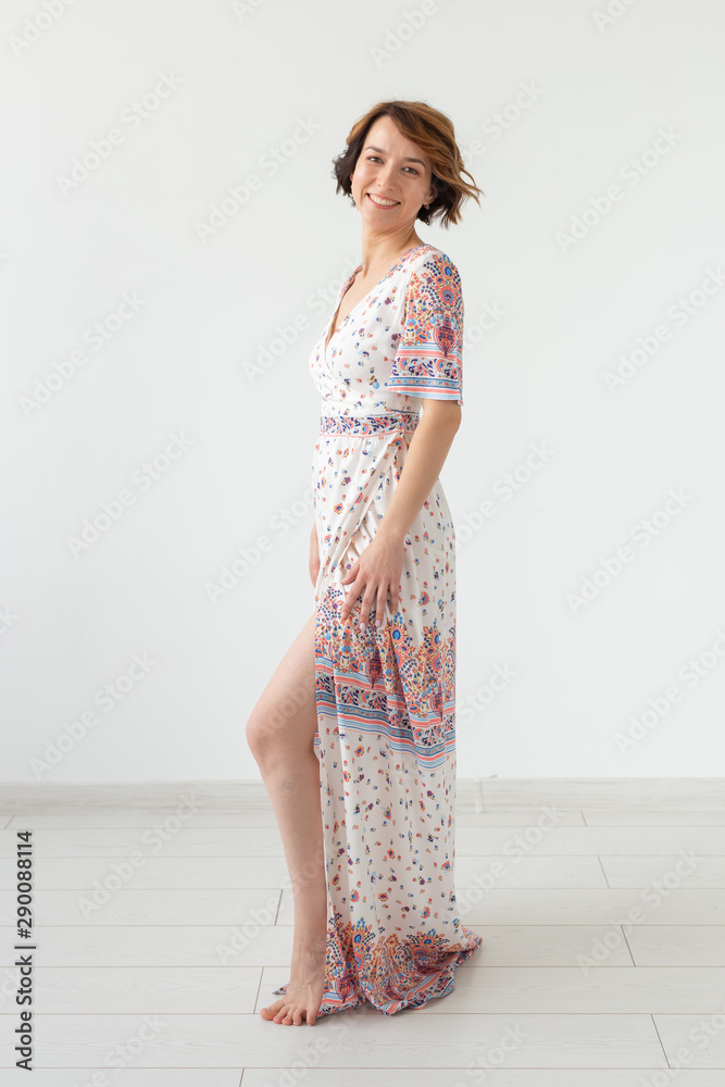 Clothing designer and people concept - woman in floor-length dress over the white background Clothing designer and people concept - woman in floor-length dress over the white background