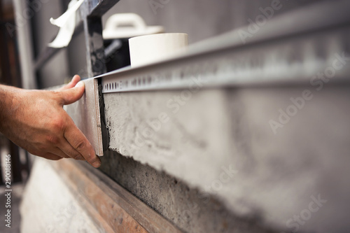 Construction worker hand glues ceramic tile to the edge of the balcony.