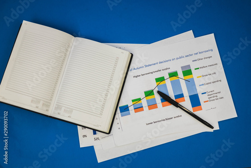 a pile of documents along with a notebook and pen lying on the blue table.