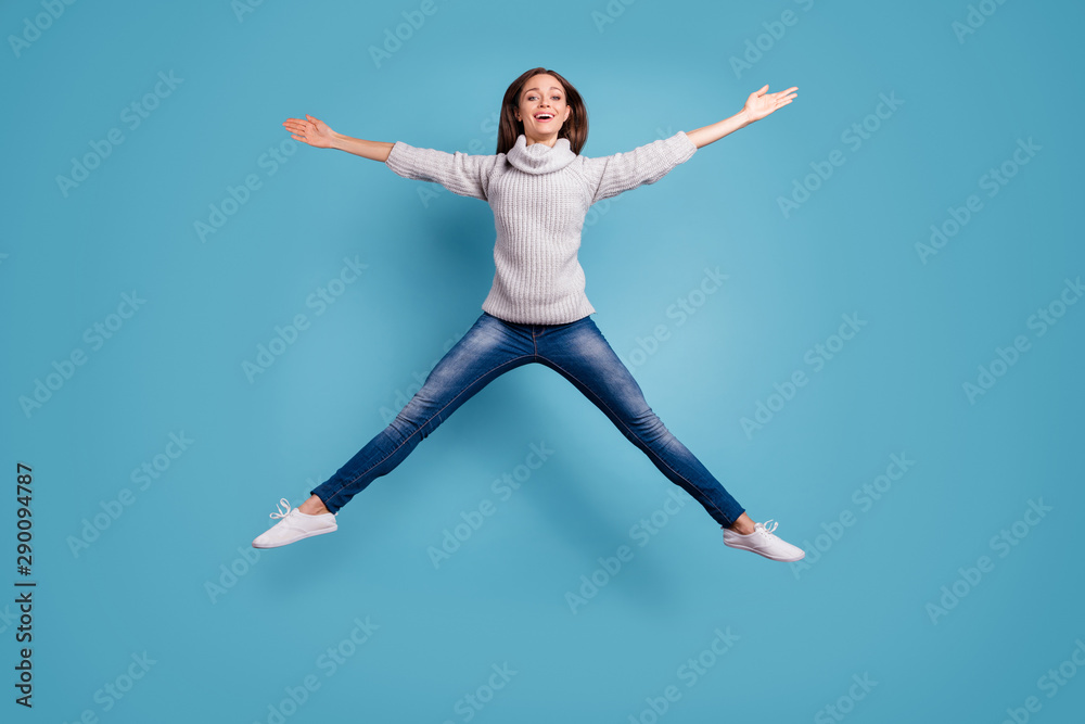 Full size photo of cute candid girl jump like a star feel content wear white sweater pullover denim jeans sneakers isolated over blue color background