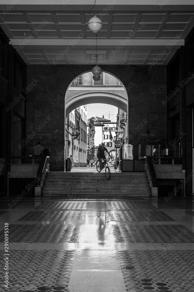 Games of the shadows and the light. The historical city center of Brescia, Italy street photography with biker going down from the stairs.