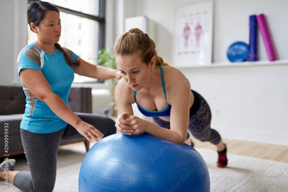 Fototapeta premium Chinese woman personal trainer during a workout session with an attractive blond client in a bright medical office