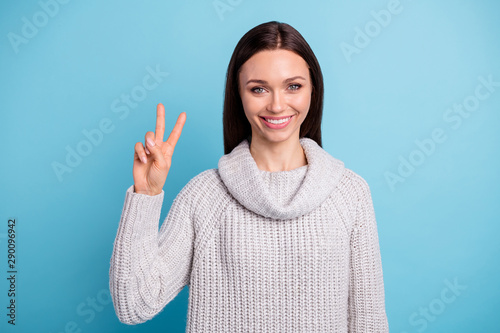 Portrait of lovely charming female person have vacation make v-sign wear white knitted jumper isolated over blue color background