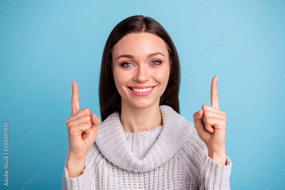 Close up photo of positive cheerful girl promoter choose ads decide adverts look up point index finger wear white knitted jumper isolated over blue color background Close up photo of positive cheerful girl promoter choose ads decide adverts look up point index finger wear white knitted jumper isolated over blue color background