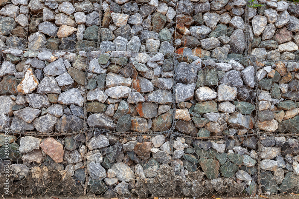 Stone walls for blocking the collapsing stone. Stone background. Stone wall covered with a net. stone gabion wall. Stone walls for blocking the collapsing stone. Stone background. Stone wall covered with a net. stone gabion wall.