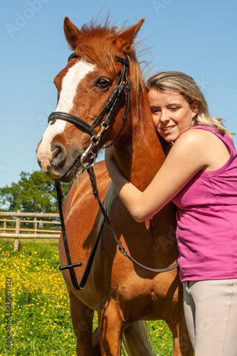 Young girl with horse, hugging in the field. 