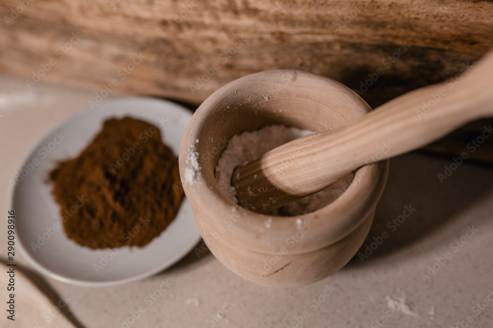 On the table in the bakery is a bowl of cinnamon, powdered sugar and a rolling pin - preparation for baking cookies On the table in the bakery is a bowl of cinnamon, powdered sugar and a rolling pin - preparation for baking cookies