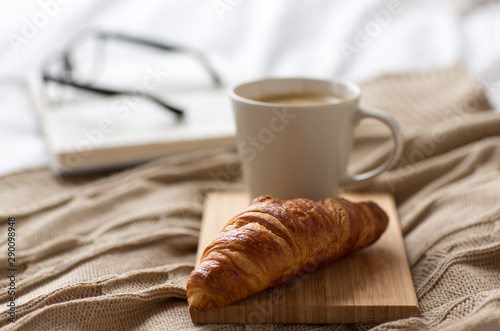 Canvastavla food, eating and breakfast concept - croissant and cup of coffee on bed at cozy