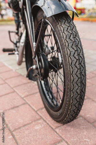 The front wheel of the motorcycle with a drum brake and a cable to it is the front fork with a shock absorber and a spring on a homemade motorcycle in a vintage style