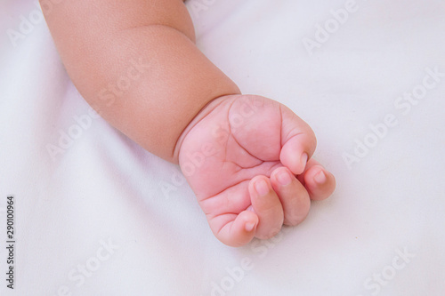 Asian baby's hands are sleeping on a white bed sheet with copy space