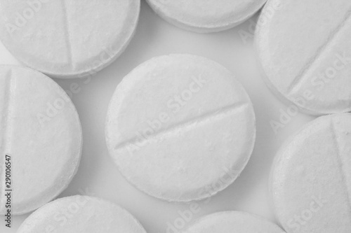 White pills with a line in the middle on a white background, texture of pills.