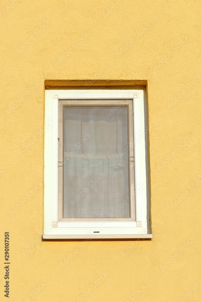 Plastic window in stucco wall. The wall is painted yellow.