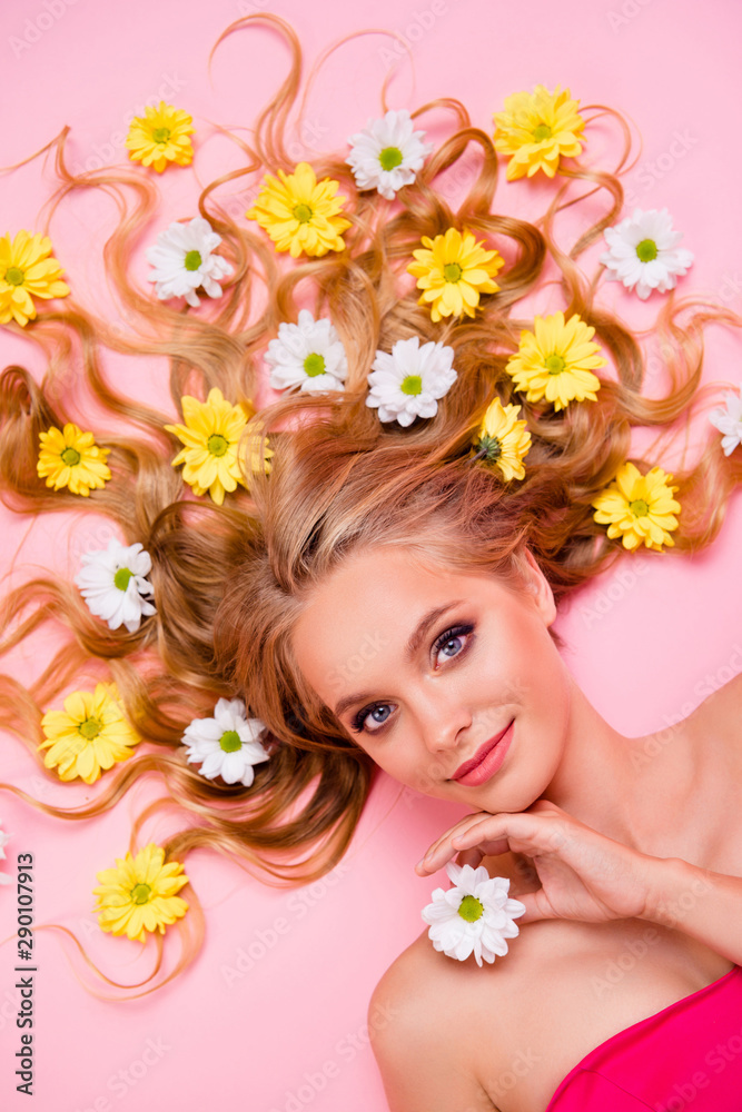 Vertical top above high angle view photo beautiful she her lady lying down among flowers long curly wavy hair one arms floral concept skin treatment overjoyed summer mood isolated pink background