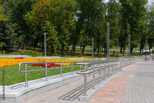 Fototapeta Naklejka Na Ścianę i Meble -  Ramp for disabled people near paved park road in big beautiful park in summer.