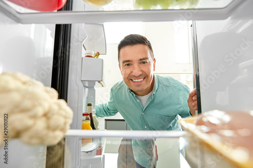 Fotografía eating and diet concept - smiling middle-aged man looking for food in fridge at
