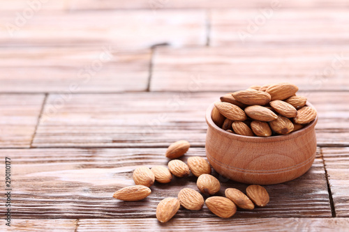 Almonds in bowl on brown wooden table