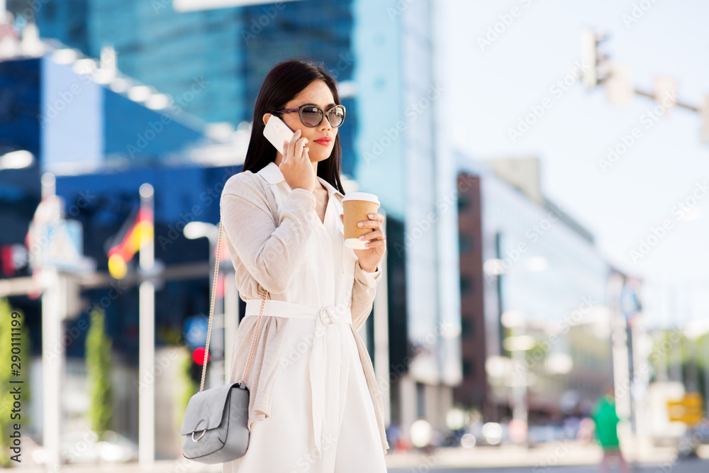 Fototapeta premium communication, lifestyle and technology concept - young asian woman in sunglasses with takeaway coffee cup calling on smartphone on city street