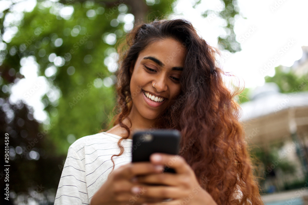 Close up beautiful young indian woman smiling and looking at cellphone Close up beautiful young indian woman smiling and looking at cellphone