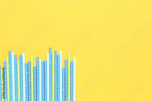 Colorful paper straws on yellow background