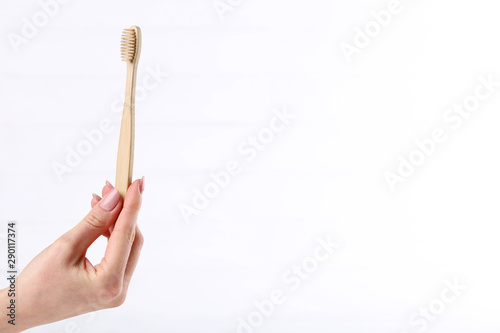 Bamboo toothbrush in female hand on white background