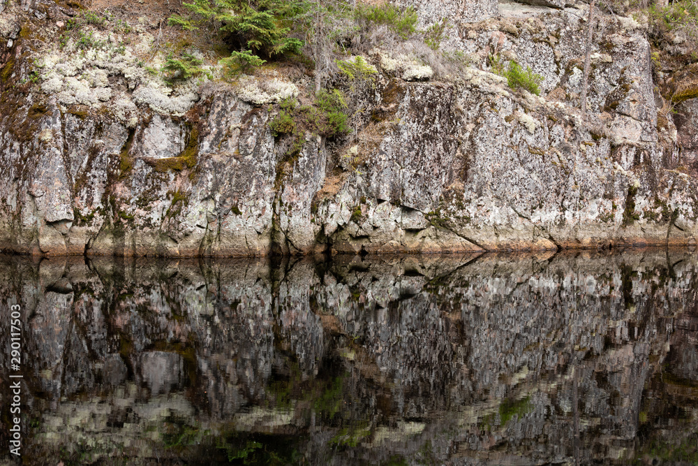 Rock reflectin to still water in forest lake Rock reflectin to still water in forest lake