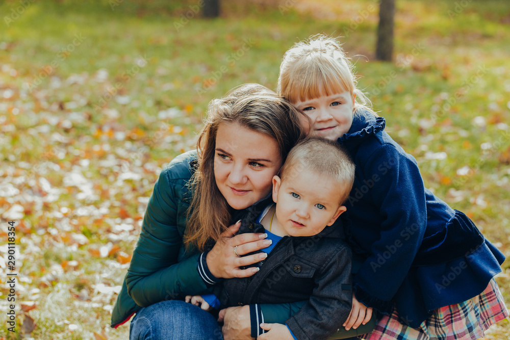 Beautiful young mother with daughter and son are walking in the autumn park. close-up portrait Beautiful young mother with daughter and son are walking in the autumn park. close-up portrait